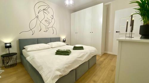 a bedroom with a bed with a drawing on the wall at Apartament GREEN CROWNS in Płock