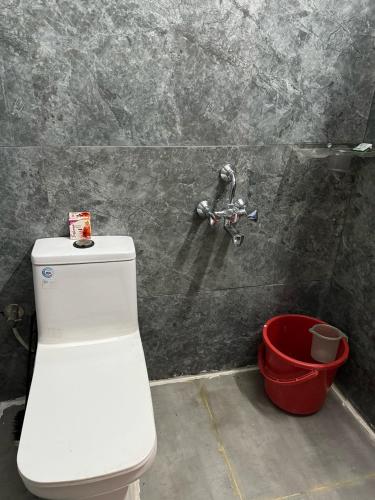 a bathroom with a white toilet and a bucket at Leela Homestay Indore - Tulip - 2 BHK Luxury apartment in Indore