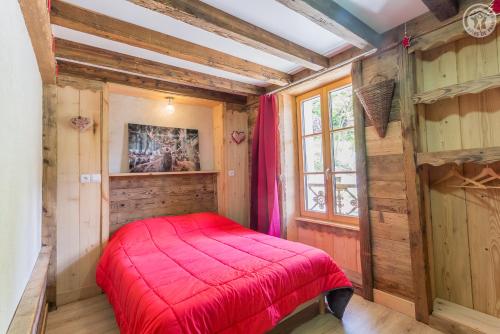 Un dormitorio con una cama roja en una habitación con paredes de madera. en LA DENT PARRACHEE, en Termignon