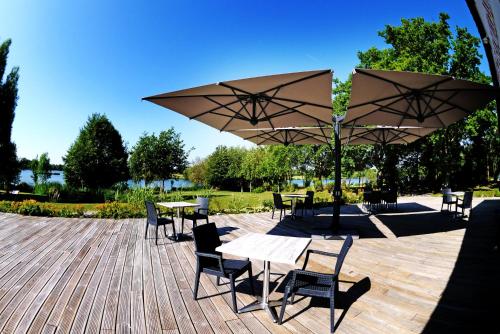 a patio with tables and chairs and umbrellas at Pescalis Résidence Les Maisons du Lac in Moncoutant