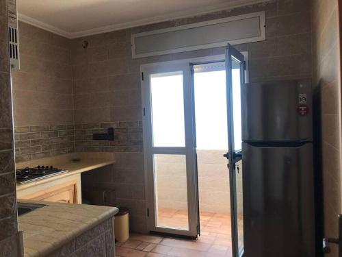 a kitchen with a stainless steel refrigerator and a window at Asilah beach Apartment seaview in Asilah
