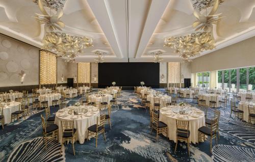 - une salle de banquet avec des tables et des chaises blanches dans l'établissement W Singapore - Sentosa Cove, à Singapour