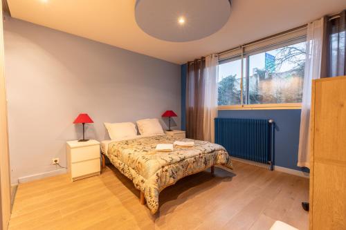 a bedroom with a bed and a large window at Appartement avec jardin, idéal pour animaux - Floréal in Clermont-Ferrand