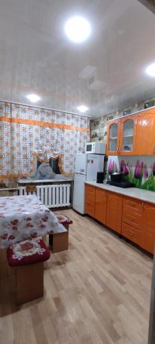 Квартиры Semey في سيمي: مطبخ مع خزائن برتقال وطاولة في الغرفة
