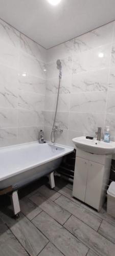 Baño blanco con bañera y lavamanos en Квартиры Semey, en Semey