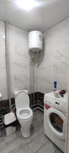 a bathroom with a toilet and a washing machine at Квартиры Semey in Semey