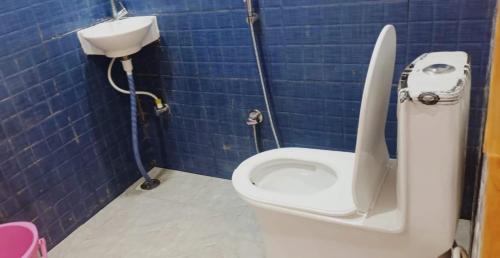 a bathroom with a toilet and a blue tiled wall at DBR GUEST HOUSE in Gorakhpur