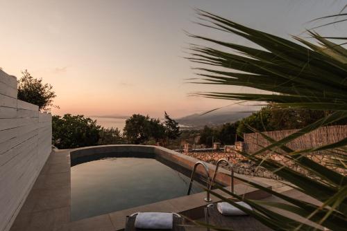 a swimming pool with a sunset in the background at Anemos in Koríthion