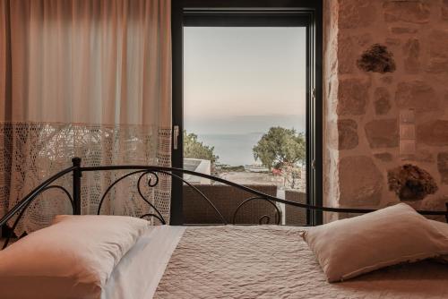 a bedroom with a bed and a large window at Anemos in Koríthion
