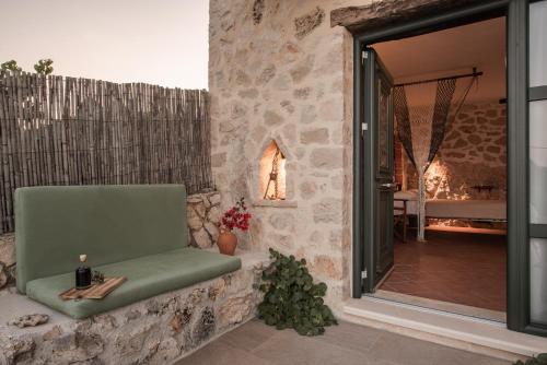 a stone walled patio with a green chair and a fireplace at Anemos in Koríthion