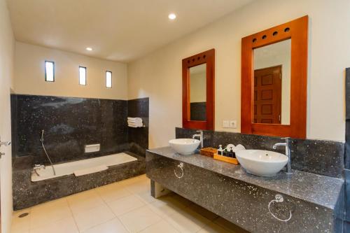a bathroom with two sinks and a bath tub at The Mutiara Jimbaran Boutique Villas in Jimbaran