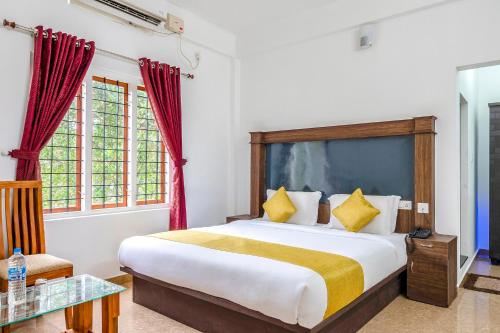 a bedroom with a bed and a table and windows at FabHotel Abrigo Residency in Munnar