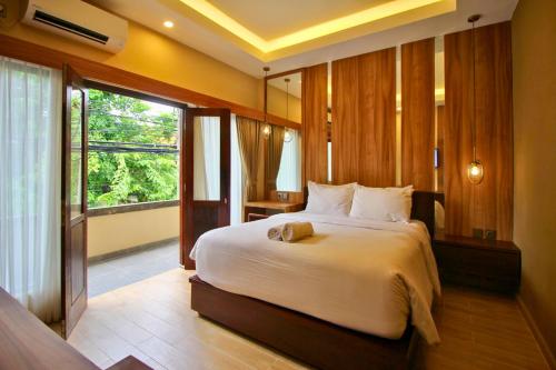 ein Schlafzimmer mit einem großen Bett und einem großen Fenster in der Unterkunft AB Hotel Kuta in Kuta