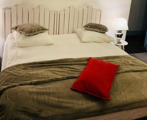 a large white bed with a red pillow on it at Mirepoix Labyrinthe chambre avec salle de bain et lit 180 cm in Mirepoix