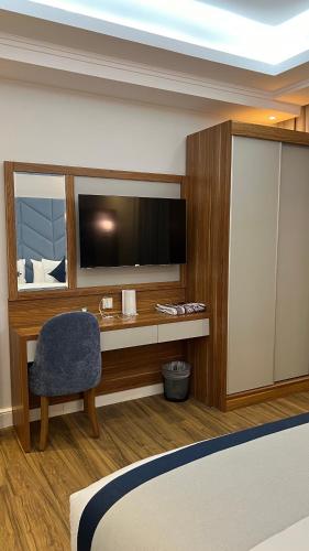 a hotel room with a bed and a tv and a chair at La Richy Jeddah in Jeddah