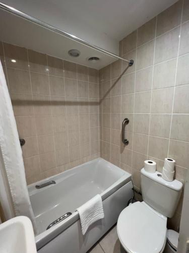 a bathroom with a tub and a toilet and a sink at Hermitage Park Hotel in Coalville