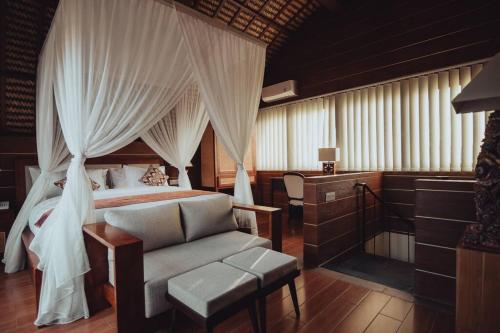 sypialnia z łóżkiem z baldachimem i krzesłem w obiekcie Amazing 1 Bedroom Villa in Ubud w mieście Ubud