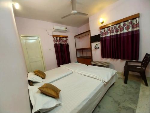 een slaapkamer met een groot wit bed en een stoel bij Aryan guest house in Bodh Gaya