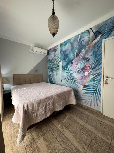 a bedroom with a bed with a mural on the wall at Minha casa in Governador Celso Ramos
