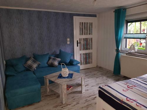 uma sala de estar com um sofá azul e uma mesa em Ferienwohnung Klabunde em Eggesin