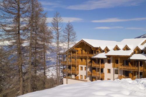 un complexe enneigé avec des arbres enneigés dans l'établissement Madame Vacances Les Balcons Des Airelles, aux Orres