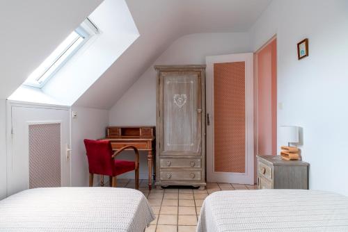 - une chambre avec deux lits, un bureau et une chaise rouge dans l'établissement Jacinthe - Appt dans une villa néo-bretonne, à Plomeur
