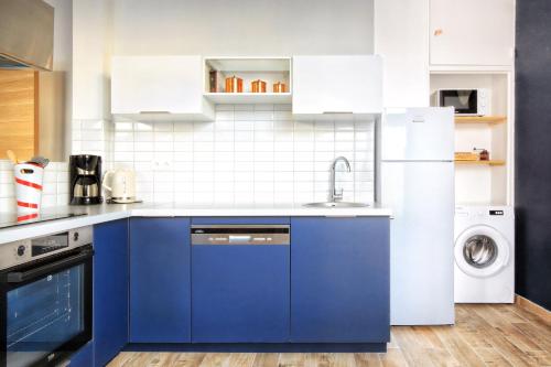 La cuisine est équipée de placards bleus et d'un réfrigérateur blanc. dans l'établissement Les Sables D'or - Joli T3 200m de la plage, à Barneville-Carteret