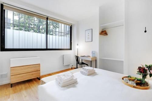 - une chambre blanche avec une grande fenêtre et un lit dans l'établissement Charming Appartements for 4 people – Le Marais, à Paris