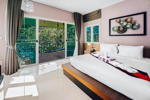 Bangnu Greenery Resort في Takua Thung: غرفة نوم بسرير كبير ونافذة كبيرة