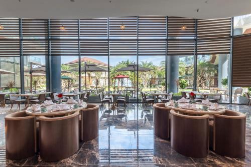 a dining room with tables and chairs and large windows at KOI Resort & Residence Da Nang - Inclusive Spa access in Da Nang