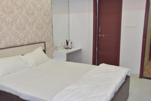 a bedroom with a white bed with a wooden door at Leela Homestay Indore - Orchid - One Bedroom with Hall and balcony in Indore