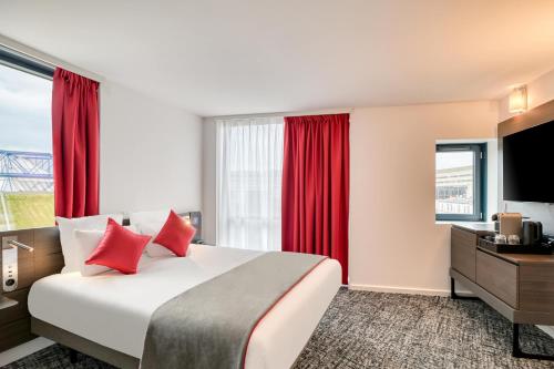 a hotel room with a large bed and red curtains at Novotel Paris Centre Bercy in Paris