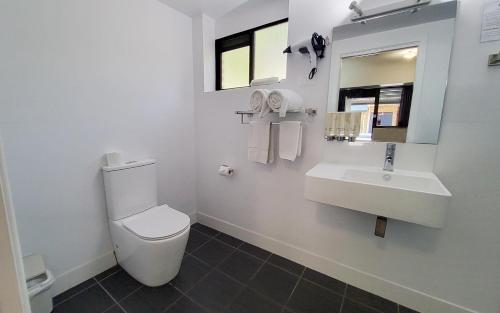 a white bathroom with a toilet and a sink at Archer Park Motel in Rockhampton