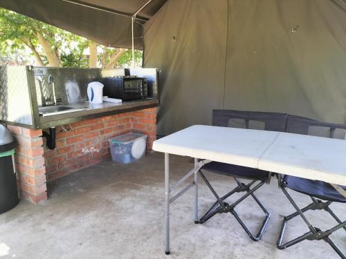 a tent with a white table and chairs in it at Riverbend Camp - Self-catering Luxury Glamping Tent in Christiana