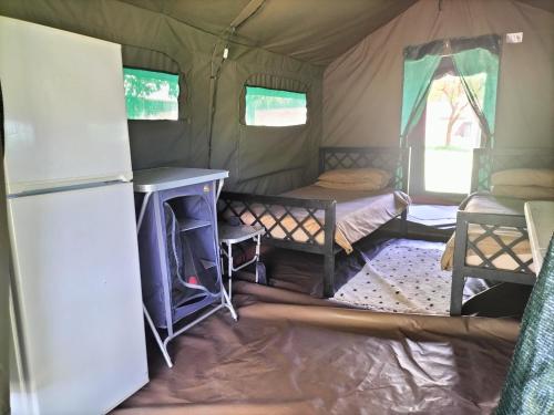 a tent with two beds and a refrigerator in it at Riverbend Camp - Self-catering Luxury Glamping Tent in Christiana