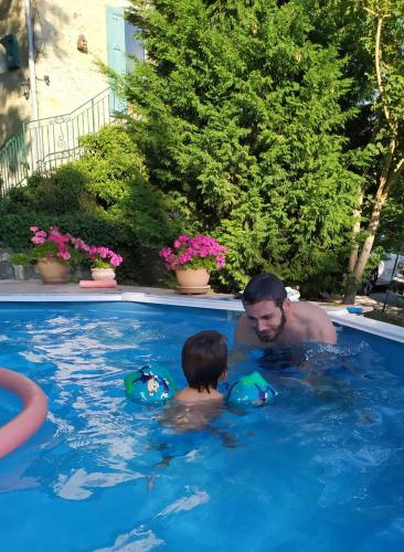 un homme et un garçon dans une piscine dans l'établissement Gite Arthur et Germaine Maisonnette à la campagne avec un grand jardin, à Saint-Jeoire-Prieuré