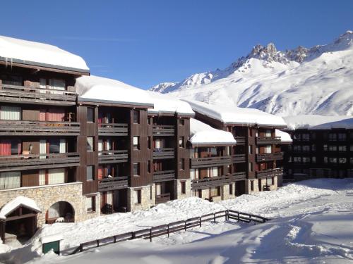a building covered in snow with mountains in the background at Résidence Creux de l'ours D et C in Méribel