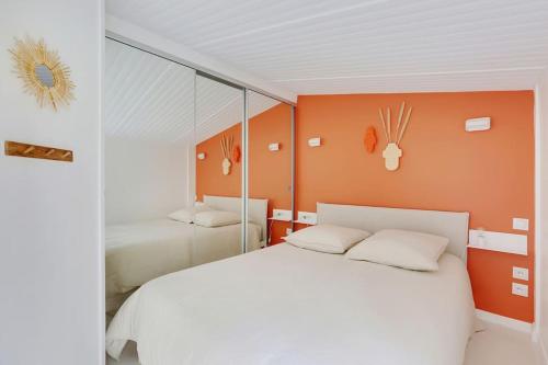 une chambre avec un lit blanc et un mur orange dans l'établissement Jardin plaisance, à Paris