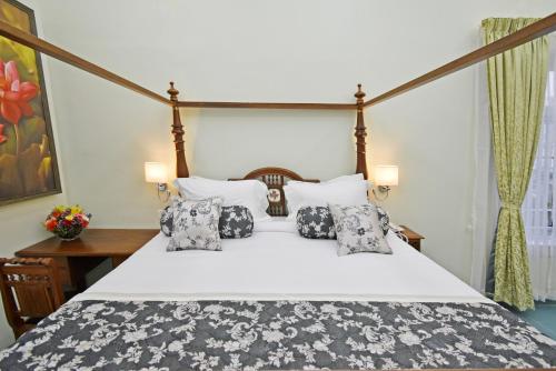 1 dormitorio con 1 cama blanca grande con almohadas en Le Colonial Suites, en Pondicherry