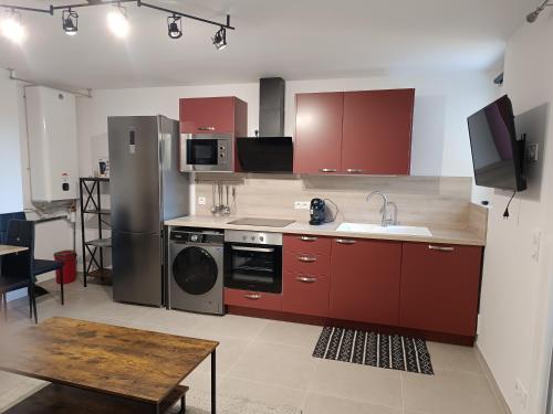 uma cozinha com armários vermelhos e electrodomésticos de aço inoxidável em appartement centre ste maxime, 100 m de la plage em Sainte-Maxime