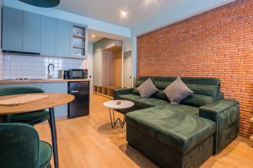 a living room with a green couch and a brick wall at New Gudauri Cozy Apartment with a Mountain View in Gudauri