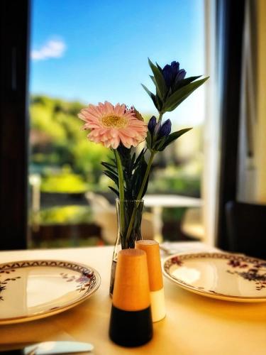 un vaso di fiori seduto su un tavolo con piatti di Sophie's Gästehaus a Meisenheim