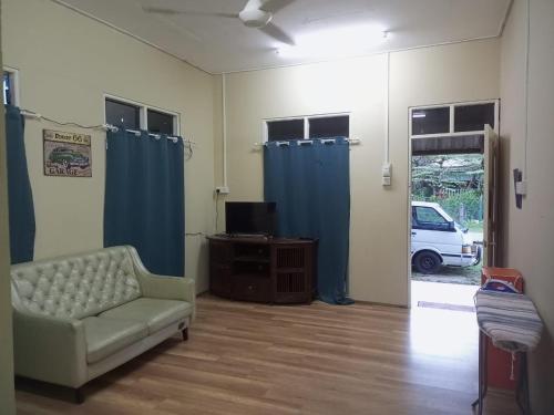 a living room with a couch and blue curtains at Bilik Bajet RM70-RM90 in Kuala Terengganu