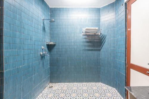 La salle de bains est pourvue d'une douche carrelée de bleu. dans l'établissement Homlee-Excellency 4BHK Apt in South Delhi, à New Delhi