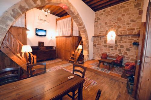 een woonkamer met een houten tafel en een stenen muur bij Villa Patitiri Traditional House in Archangelos