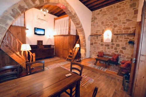 a living room with a wooden table and a stone wall at Villa Patitiri Traditional House in Archangelos