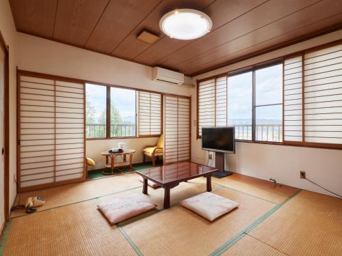 un soggiorno con finestre, tavolo e TV di Hayamasou a Tokamachi