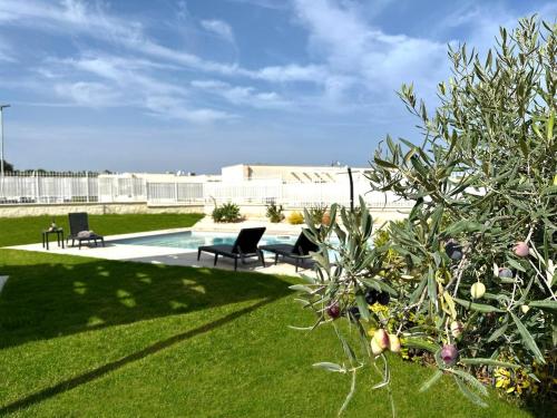 a yard with two chairs and a swimming pool at Villa Flora, Piscina Esclusiva e Mare in Brucoli
