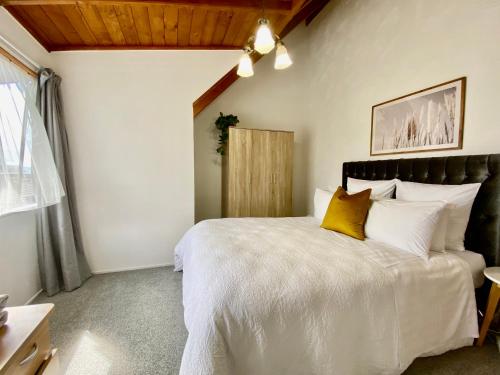 a bedroom with a large white bed with yellow pillows at The Swiss Chalet Apartment 9 - Seaview - Top Floor - Air Conditioning & Wi-Fi - Bay of Islands in Paihia