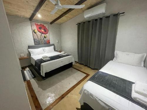 a bedroom with two beds and a painting on the wall at Kruger Wild Dog Inn in Marloth Park